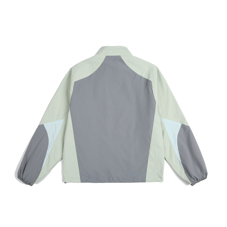 Back view of a color-block jacket in pale sage, gray, and pale blue, shown against a white background.