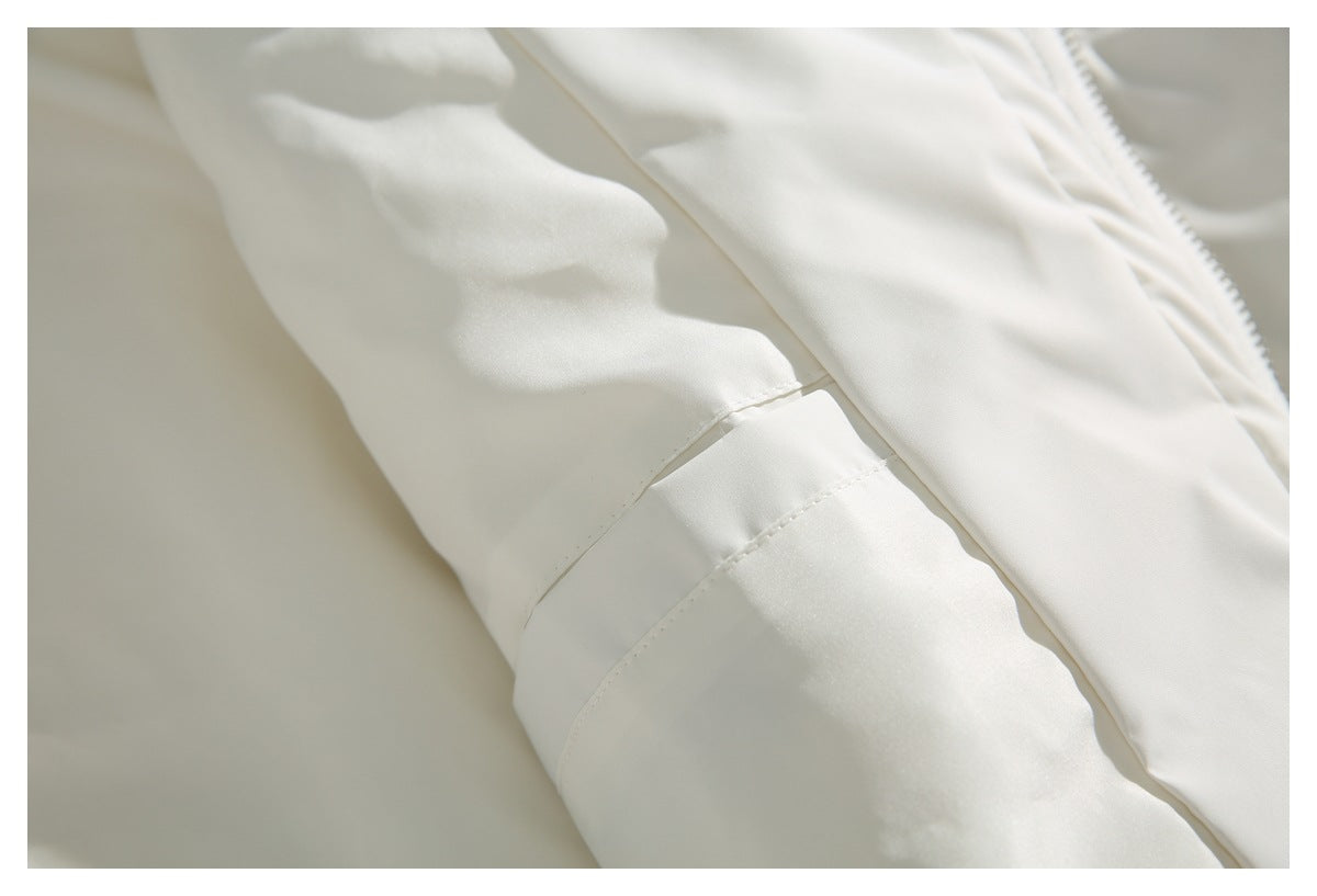 Close-up of stitched panel seams on a white jacket beside the front zipper.
