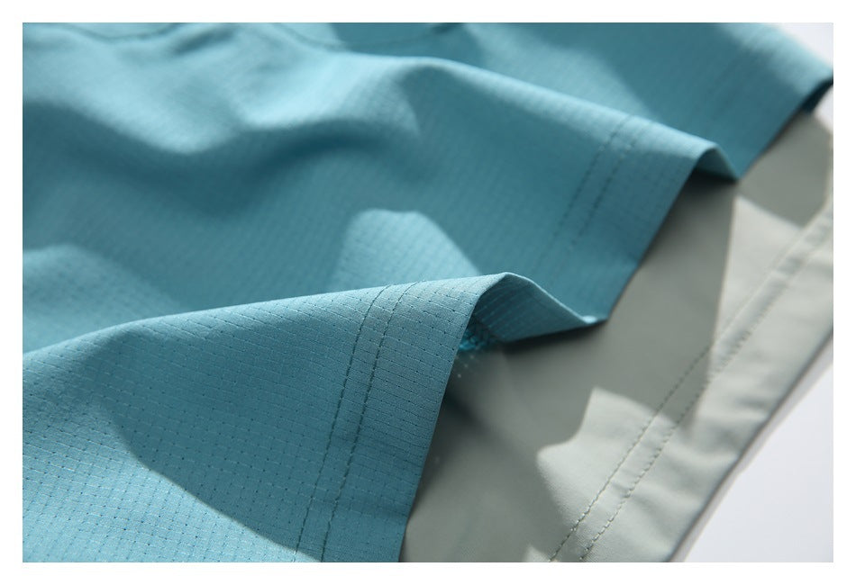 Close-up of the stitched hem on aqua shorts over a pale gray inner layer.