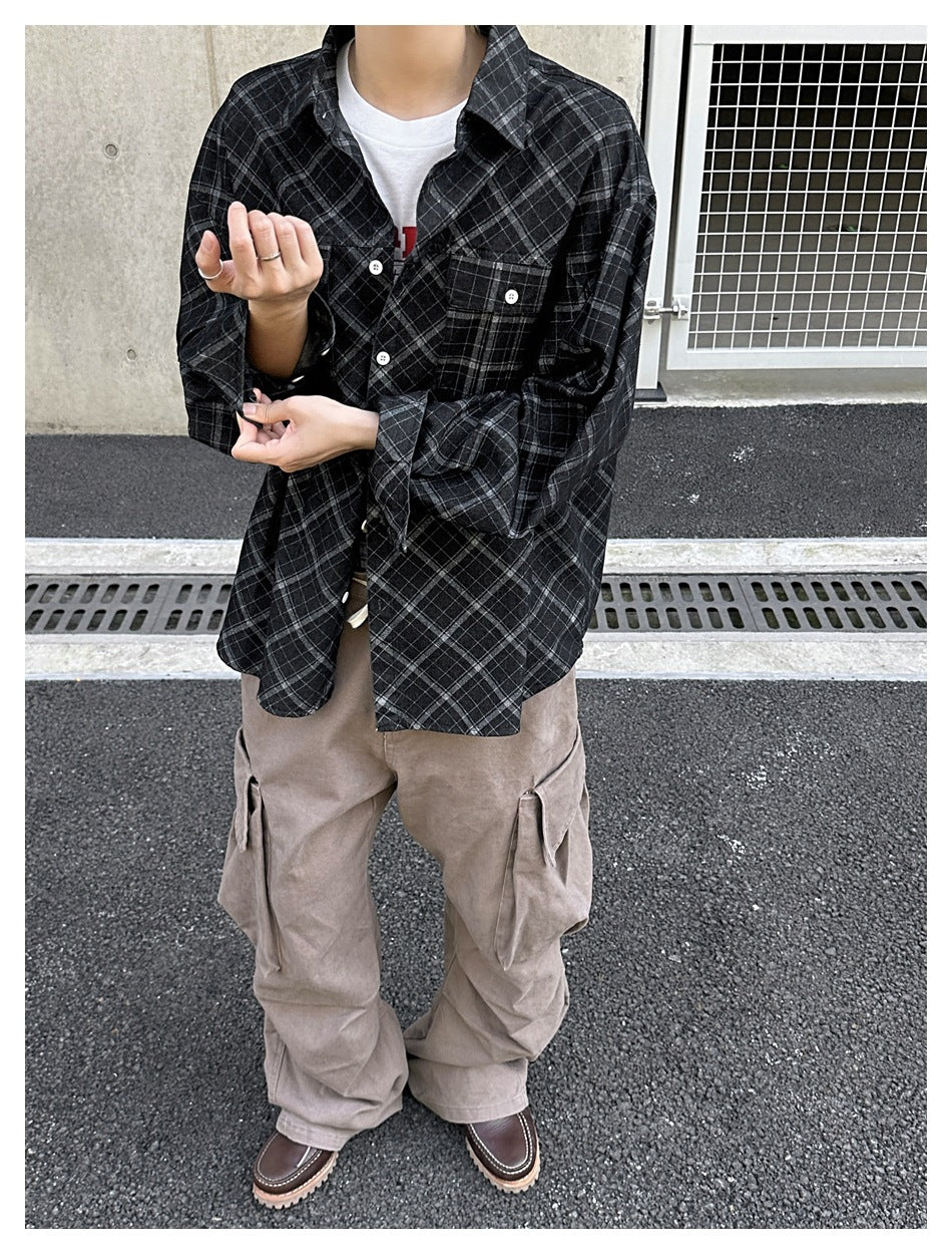 Close view of a person wearing an oversized black plaid button-up shirt with white buttons and a chest pocket.
