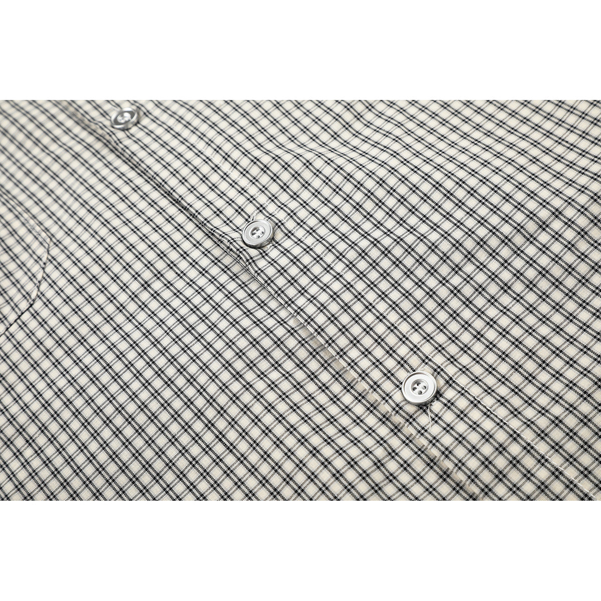 Close-up of a beige-and-black checked shirt front with white buttons and a stitched placket.