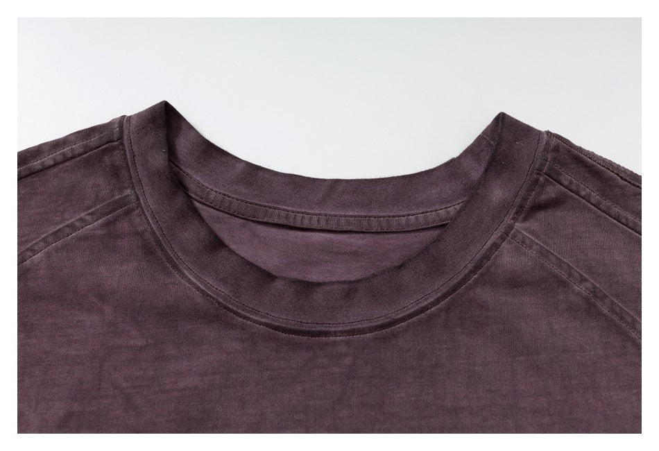 Close-up of a dark plum T-shirt's ribbed crew neckline and shoulder seams.