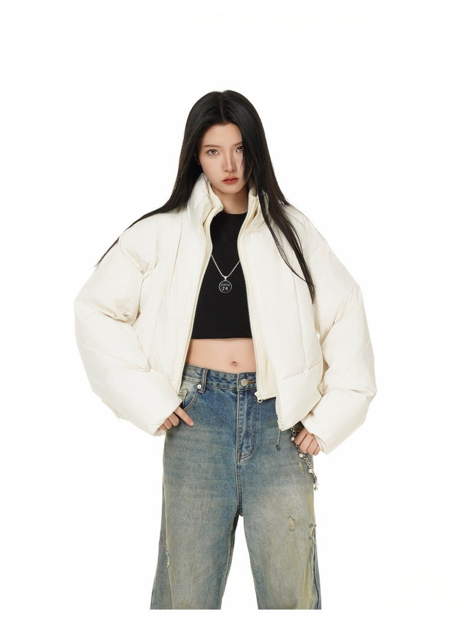 Front view of a model wearing an open ivory puffer jacket with a high collar and oversized sleeves.