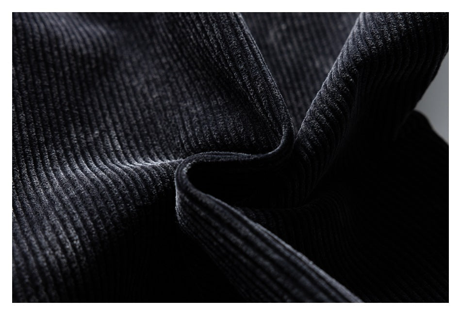 Macro view of the raised ribs and folded texture of black corduroy fabric.