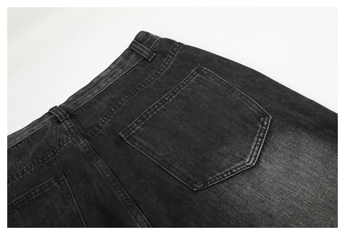 Close-up of charcoal-black jeans showing a back pocket, waistband, belt loops, and contrast stitching.