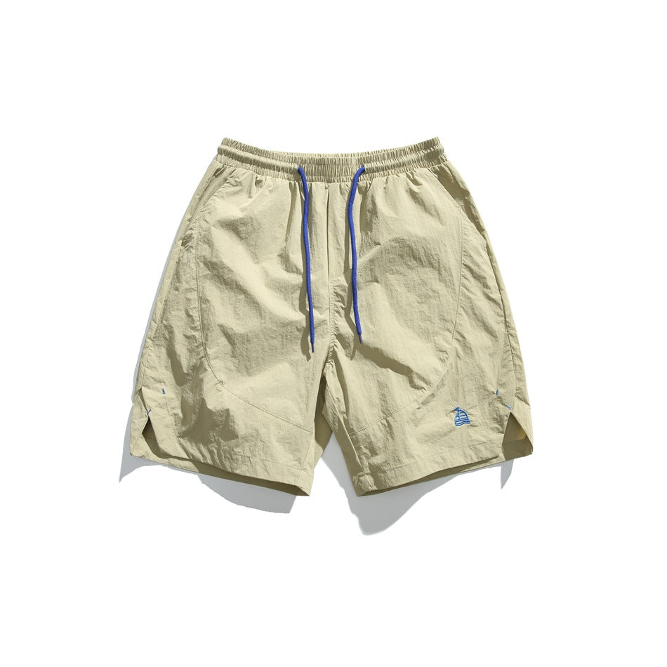 Khaki knee-length shorts with elastic waist, blue drawstring, and small embroidered sailboat, flat lay front view