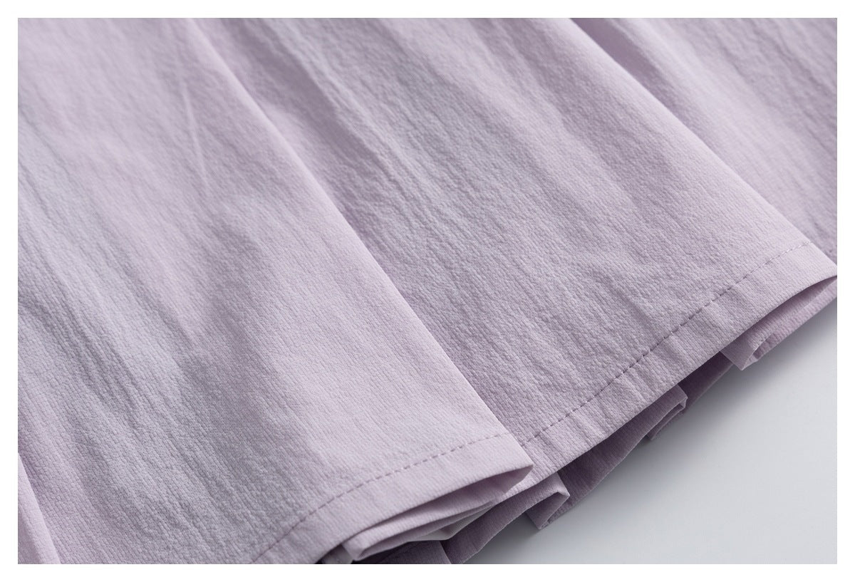 Close-up of pale lavender textured fabric with stitched hems and layered folds.