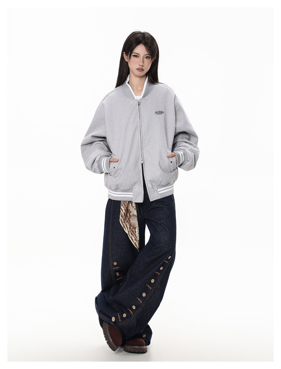 Model wearing a light gray zip-front bomber jacket with striped ribbed trim and a small oval chest emblem.