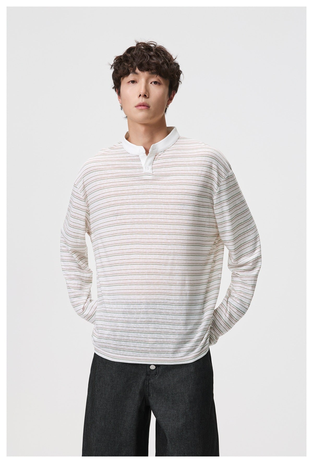 Man wearing a cream long-sleeve shirt with fine muted stripes, a white band collar and button placket.