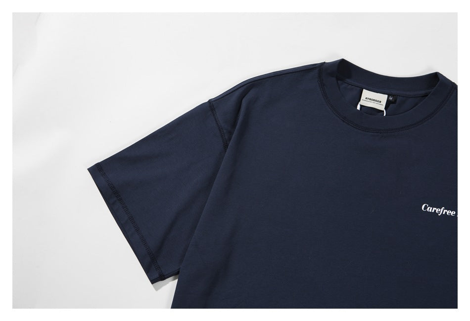 Close-up of the navy T-shirt’s sleeve and shoulder stitching, with part of the white chest print visible.