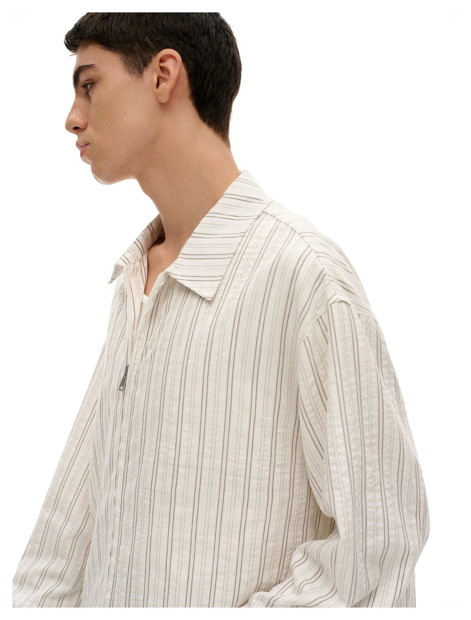Side view of a model wearing an off-white shirt with thin vertical stripes, a wide collar and front zipper.