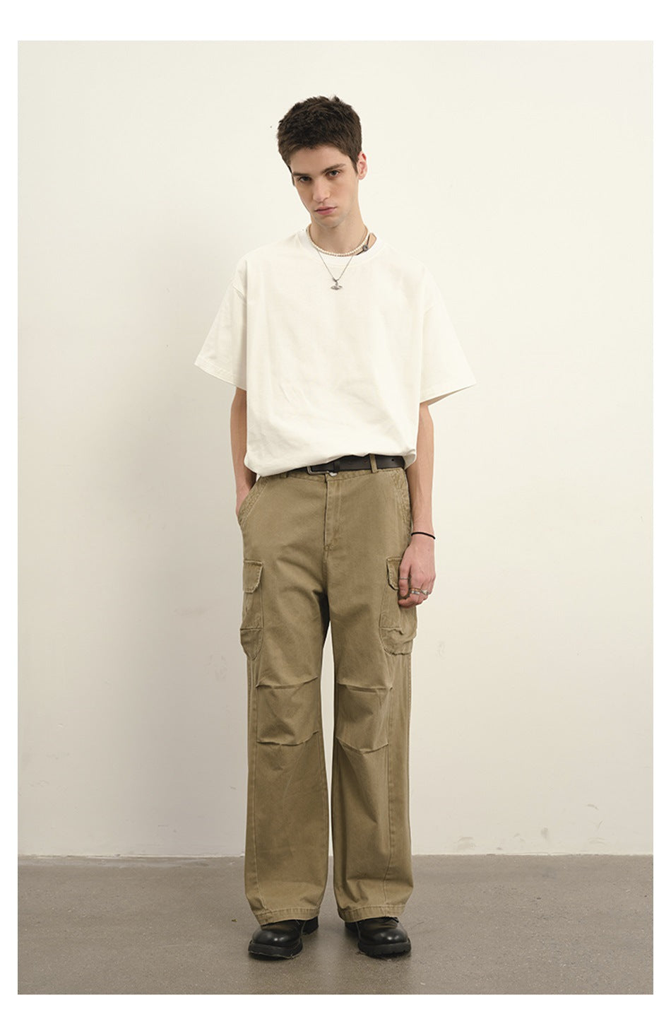 Model wearing a plain white T-shirt and loose khaki cargo pants with flap pockets and reinforced knees.