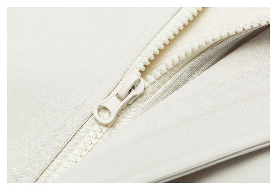 Close-up of an off-white zipper and pull between garment panels.