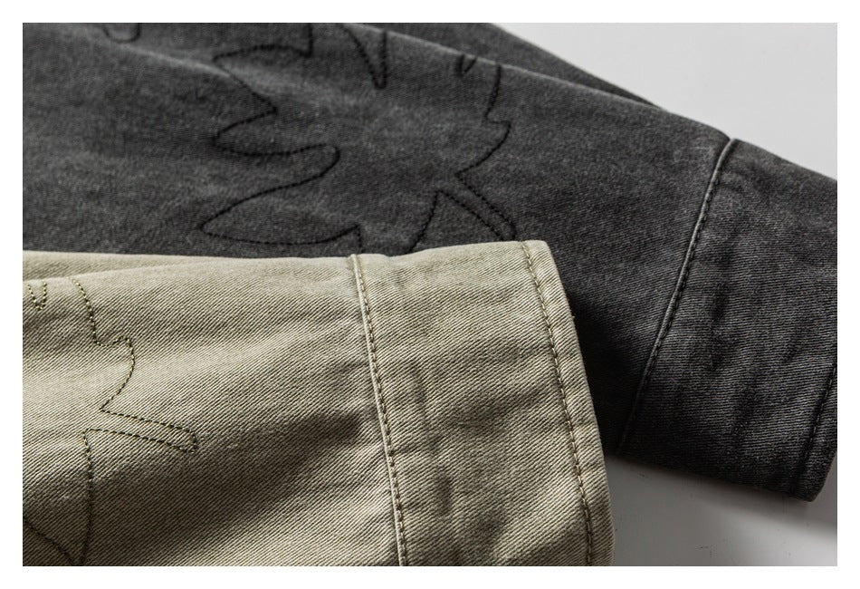 Close-up of charcoal and olive-gray shirt sleeves showing leaf-outline stitching and cuff seams.