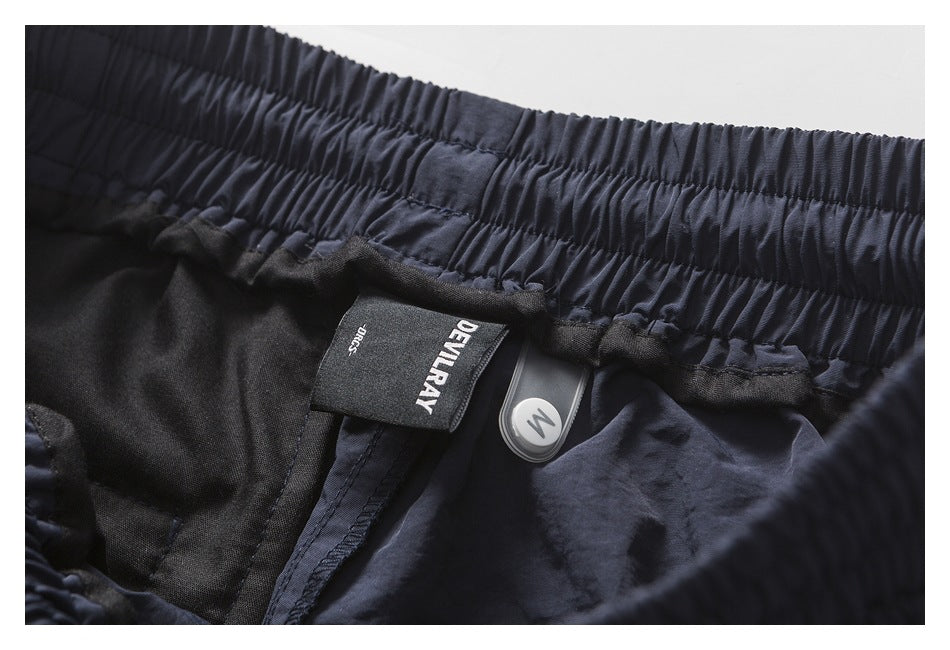 Inside view of dark navy pants with a gathered waistband, a sewn DEVILRAY label and a round size marker.