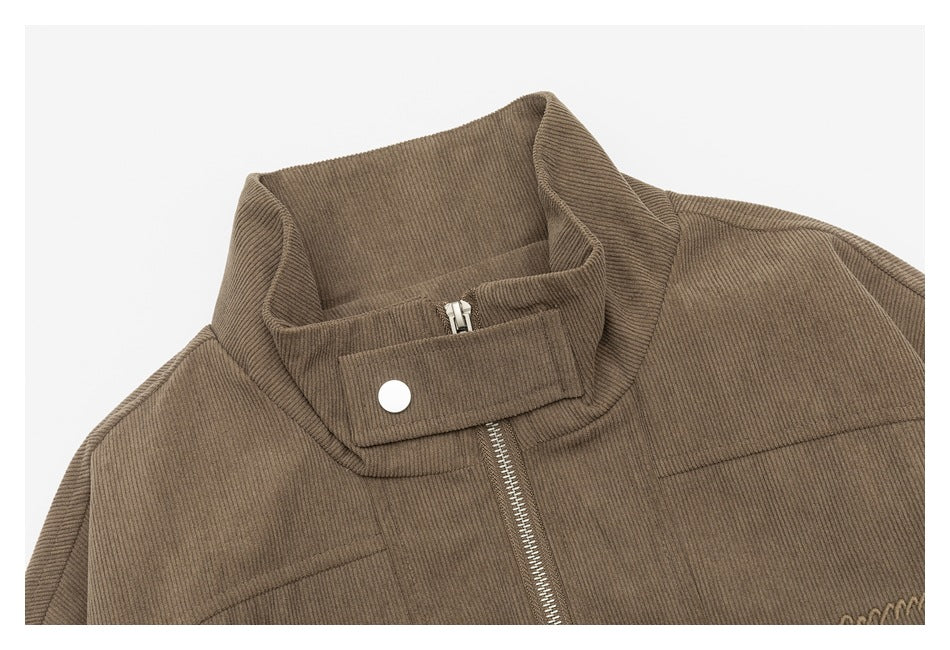 Taupe jacket detail showing a stand collar, snap-tab closure, metal zipper, and stitched panels.
