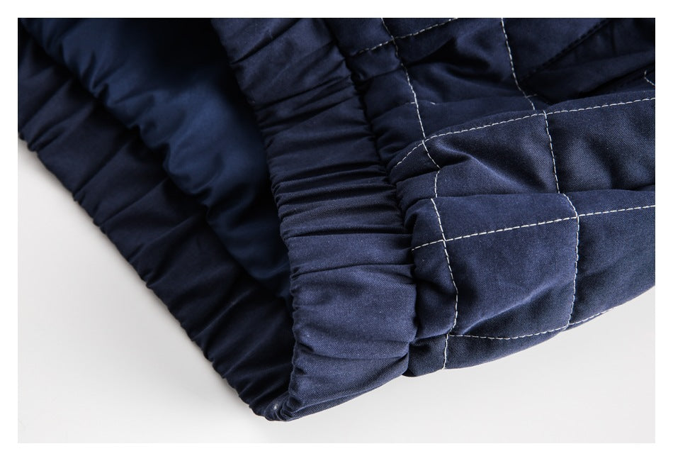Close-up of navy quilted garment with light contrast stitching and a gathered elasticized edge.