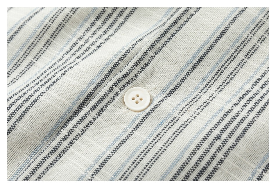 Close-up of a cream shirt button against black and pale blue stripes.
