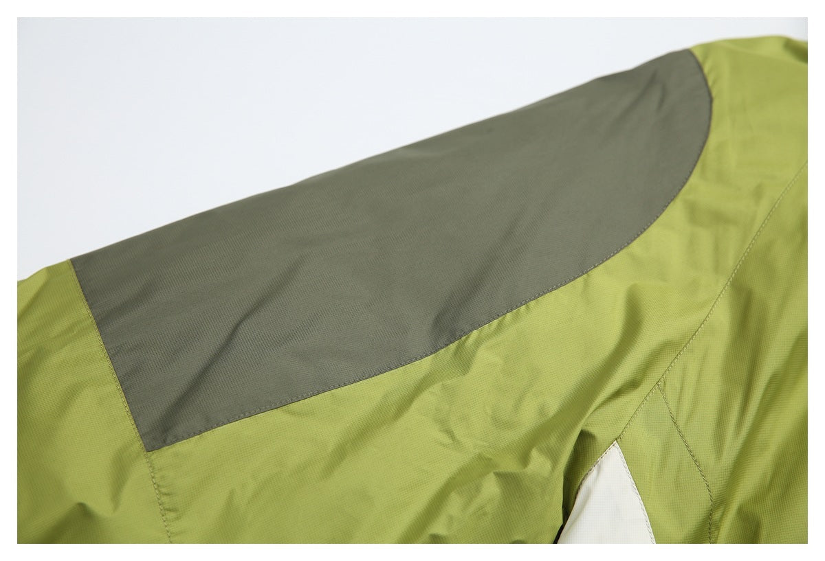 Close-up of an olive-green jacket shoulder with a broad charcoal-gray panel and a white section.