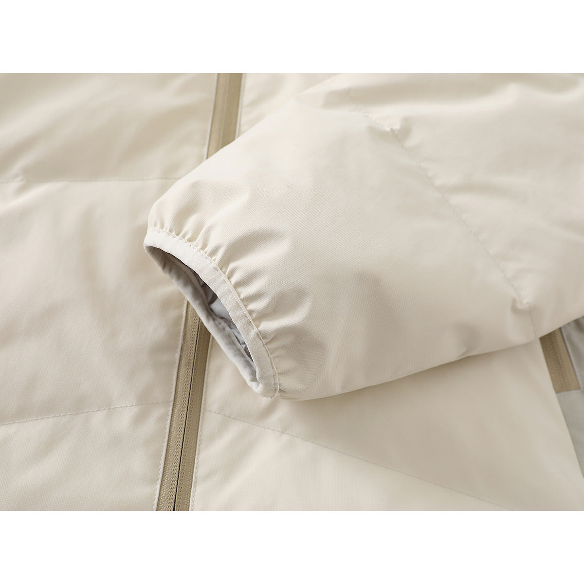 Close-up of an off-white jacket sleeve cuff and quilted panels beside the front zipper.