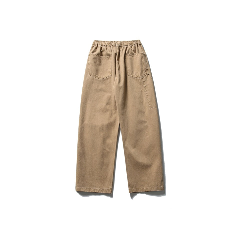 Back view of tan relaxed straight-leg trousers with an elastic waistband and two patch pockets.