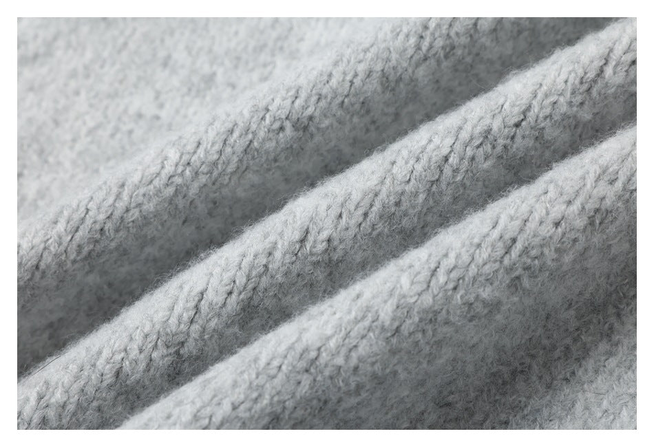 Close-up of light gray knitted fabric showing fuzzy yarn and diagonal rows of stitches.