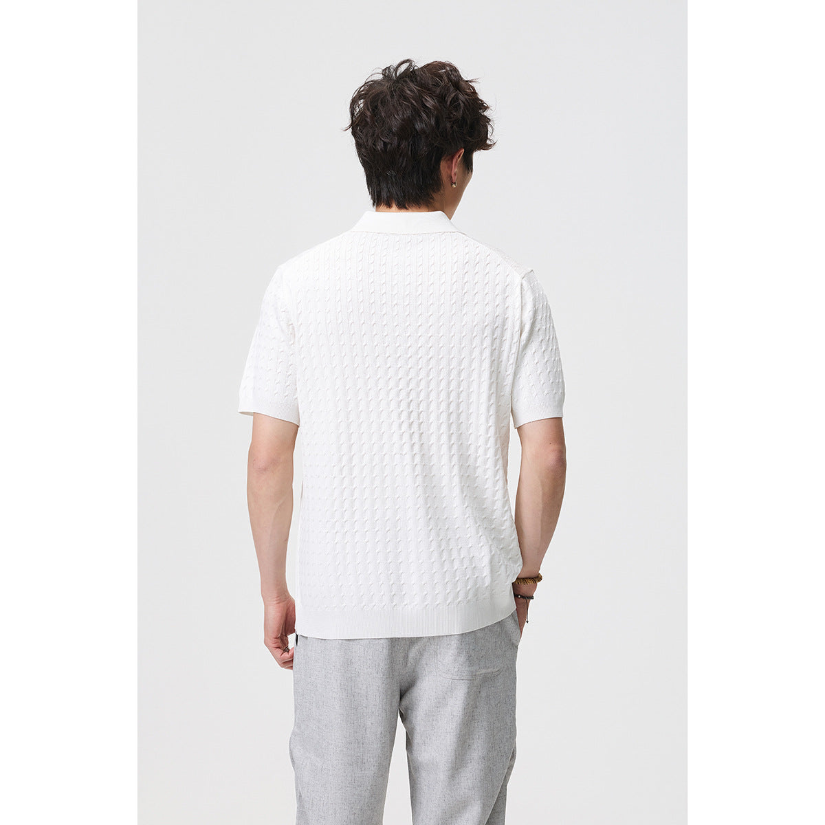 Rear view of a model wearing a white textured short-sleeve polo with a collar and ribbed hem.
