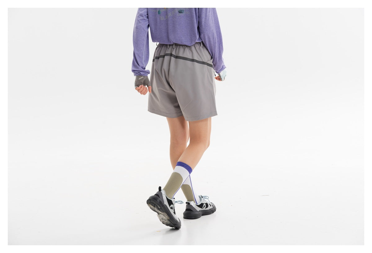 Back view of gray outdoor shorts worn by a model, with an elastic waist and a dark horizontal stripe.