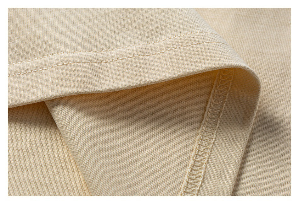 Close-up of a light beige garment hem showing topstitching and an overlocked seam.