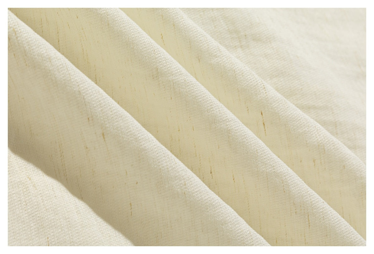 Extreme close-up of the cream shirt fabric, showing its weave and natural-looking flecks.