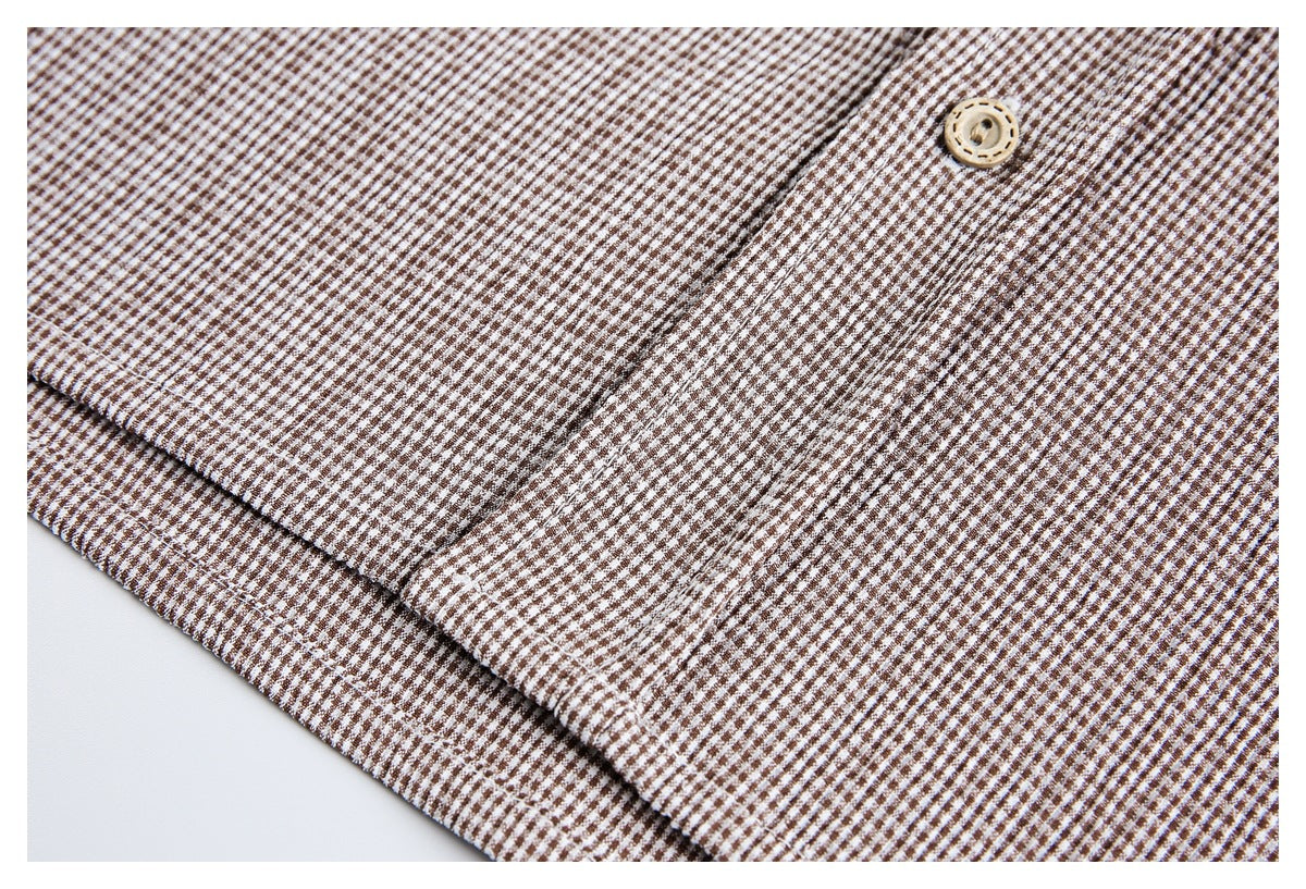 Close-up of a tan button and placket on a brown-and-white small-check garment.