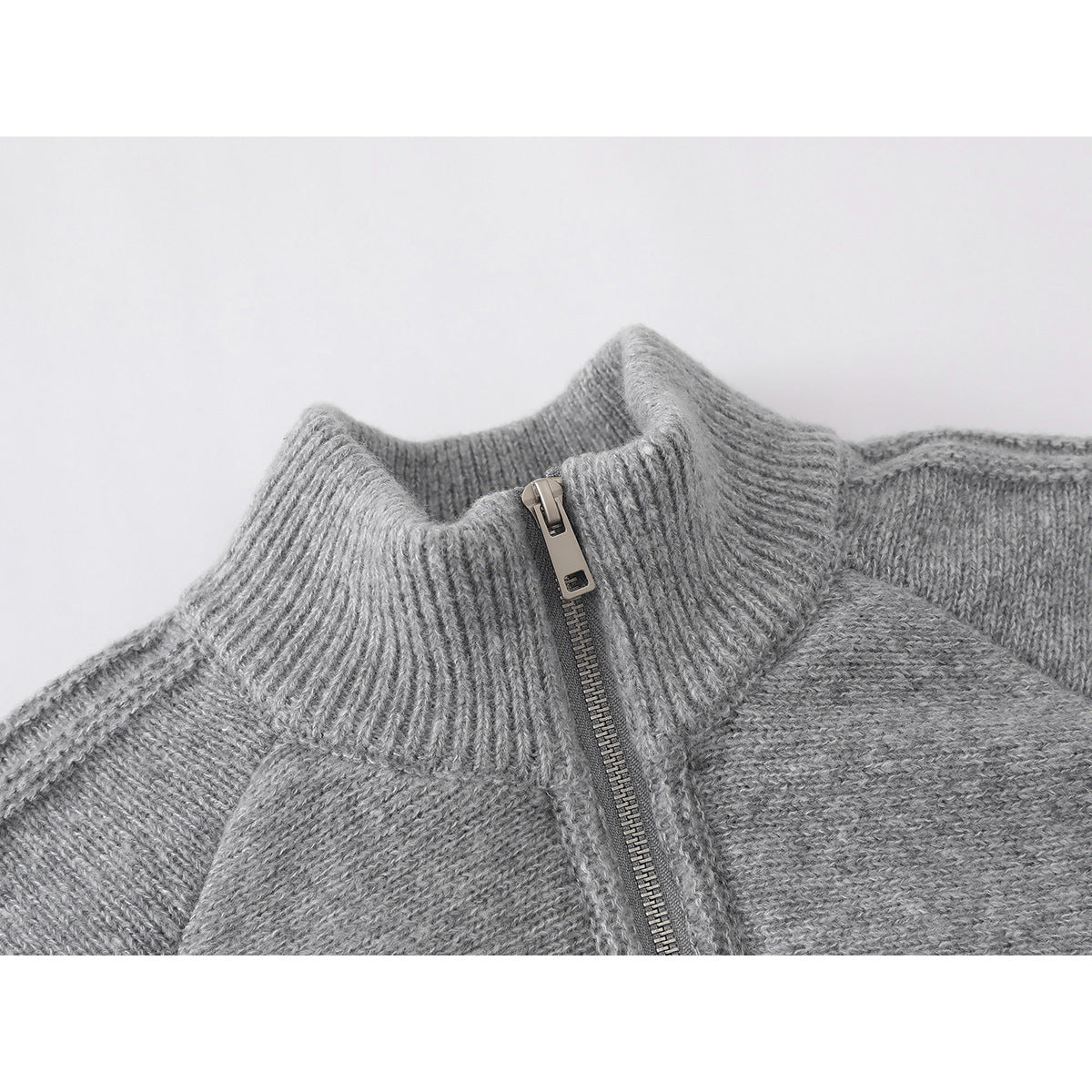 Close-up of a gray knit jacket's ribbed stand collar and front zipper.