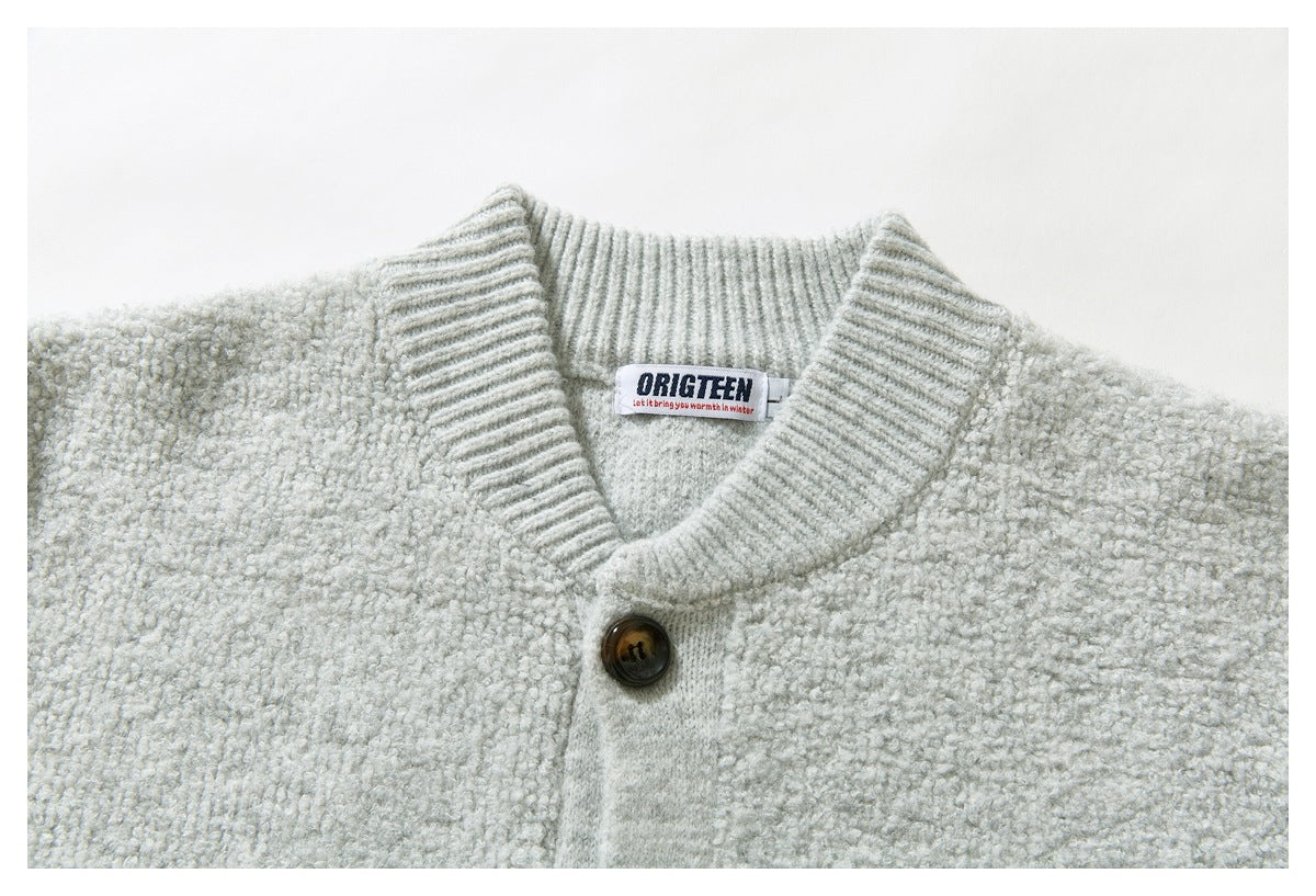 Close-up of a light gray cardigan's ribbed shawl collar, button, textured knit, and sewn neck label.