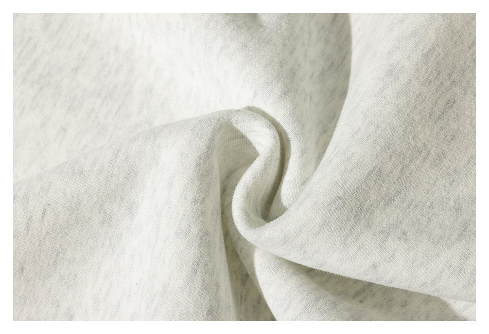 Extreme close-up of the soft-looking, light heather-gray garment fabric folded into a curve.