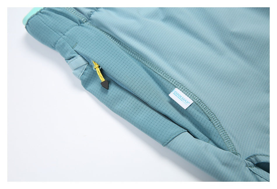 Close-up of a blue-green garment with a zippered pocket, yellow zipper pull and COOLMAX label.