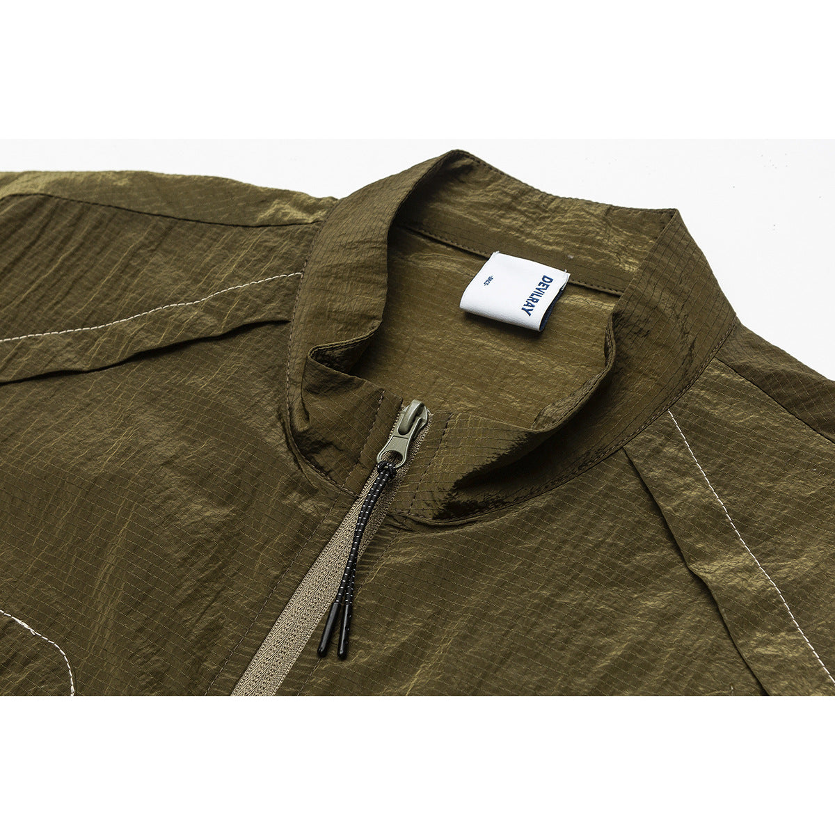 Close-up of an olive jacket’s stand collar, front zipper and white neck label.