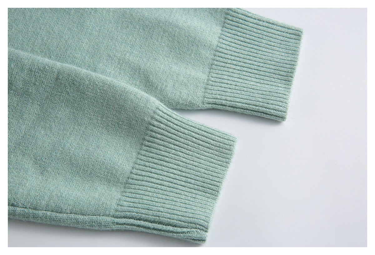 Close-up of two pale sage-green cardigan sleeves with wide ribbed cuffs.