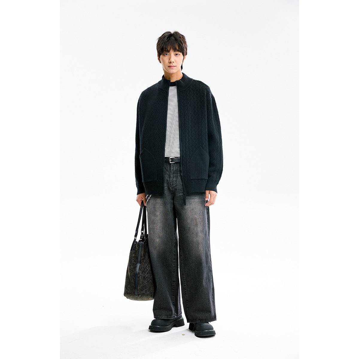 Full-length view of a model wearing an open black textured knit cardigan with front pockets.