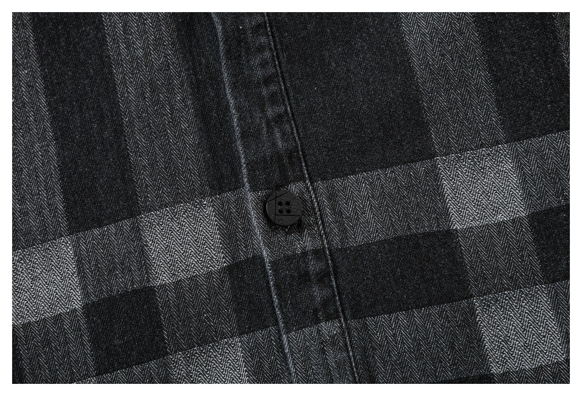 Close-up of a black button on the charcoal plaid shirt's front placket.