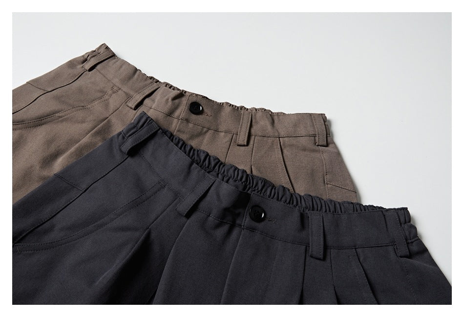Close-up of charcoal and taupe shorts waistbands, buttons, belt loops and pleats.