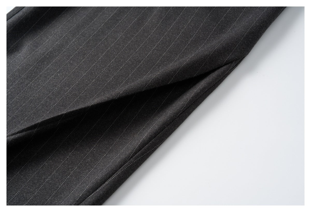 Close-up of the charcoal trousers’ fine pinstripes and stitched side seam.
