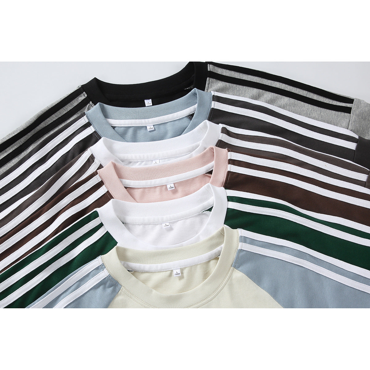 Several crew-neck T-shirts arranged in overlapping colorways, showing contrasting raglan panels and shoulder stripes.