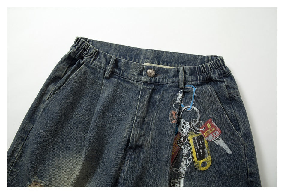 Close-up of the jeans' front waistband, button, pockets, and attached decorative keychains.