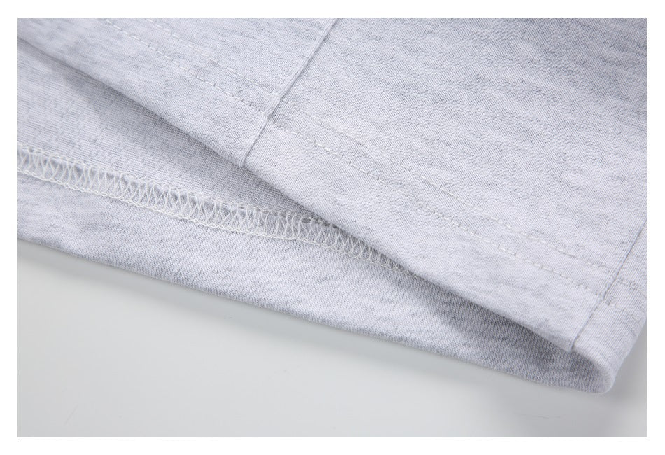 Close-up of stitching and overlock seam along the hem of a light gray heathered shirt.