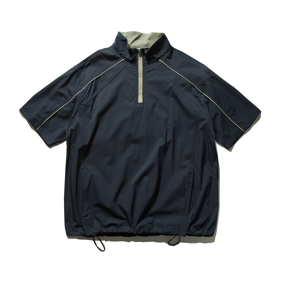 Navy short-sleeve quarter-zip jacket with stand collar, tan zipper and piping, and drawcord hem, flat lay
