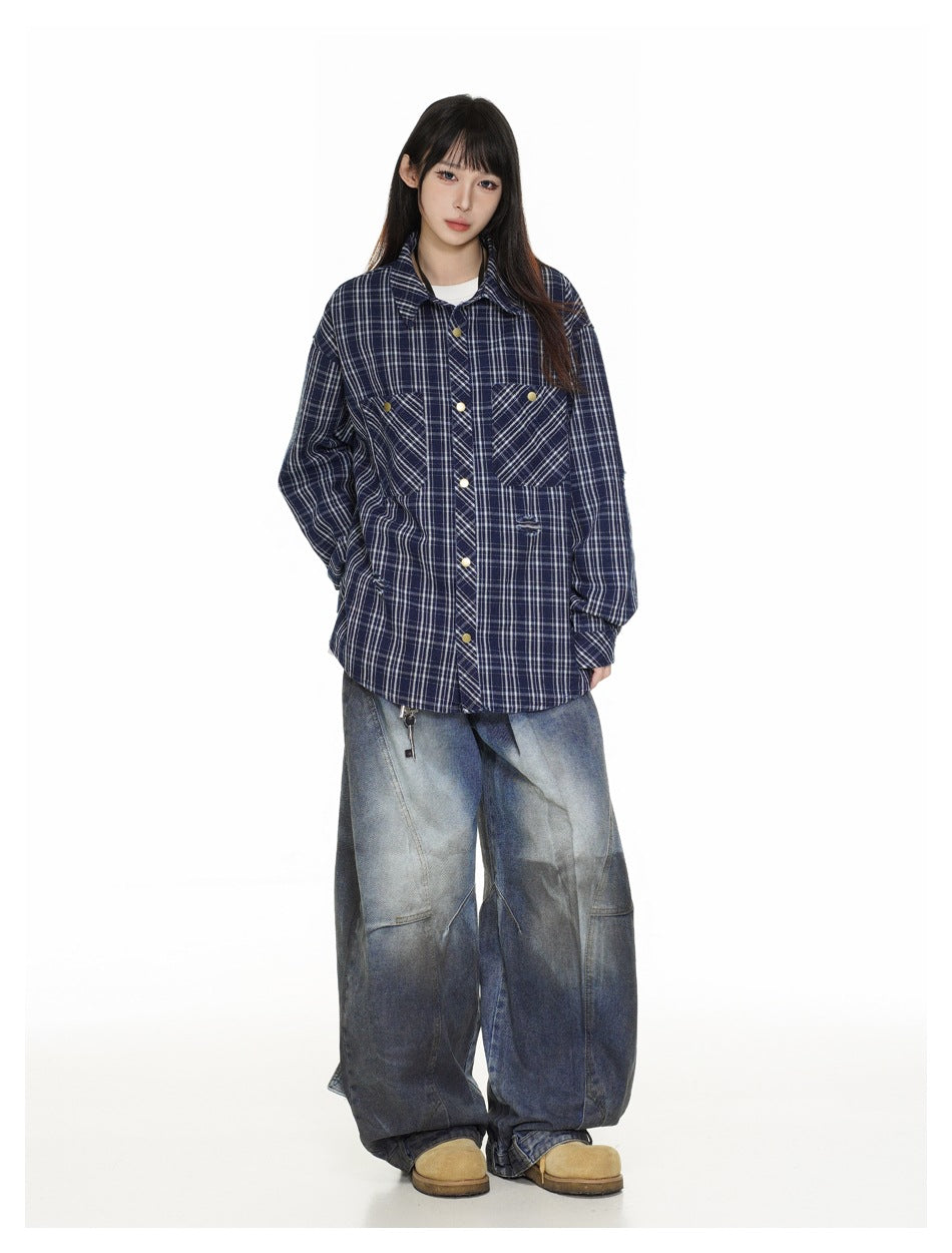 Model wearing an oversized navy plaid snap-front shirt with chest pockets and loose gray-blue jeans.