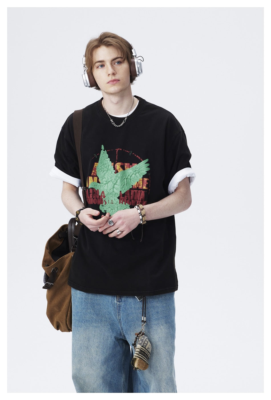 Front view of a model wearing a black T-shirt with white sleeve layers and a large raised green bird graphic.