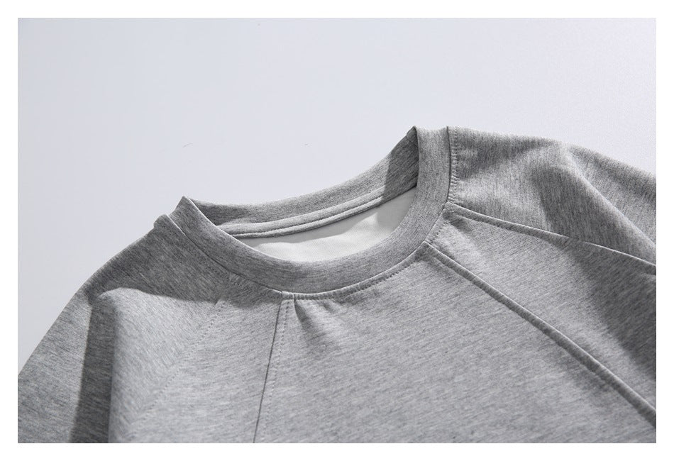 Close-up of a heather gray sweatshirt's crew neckline and raglan shoulder seams.