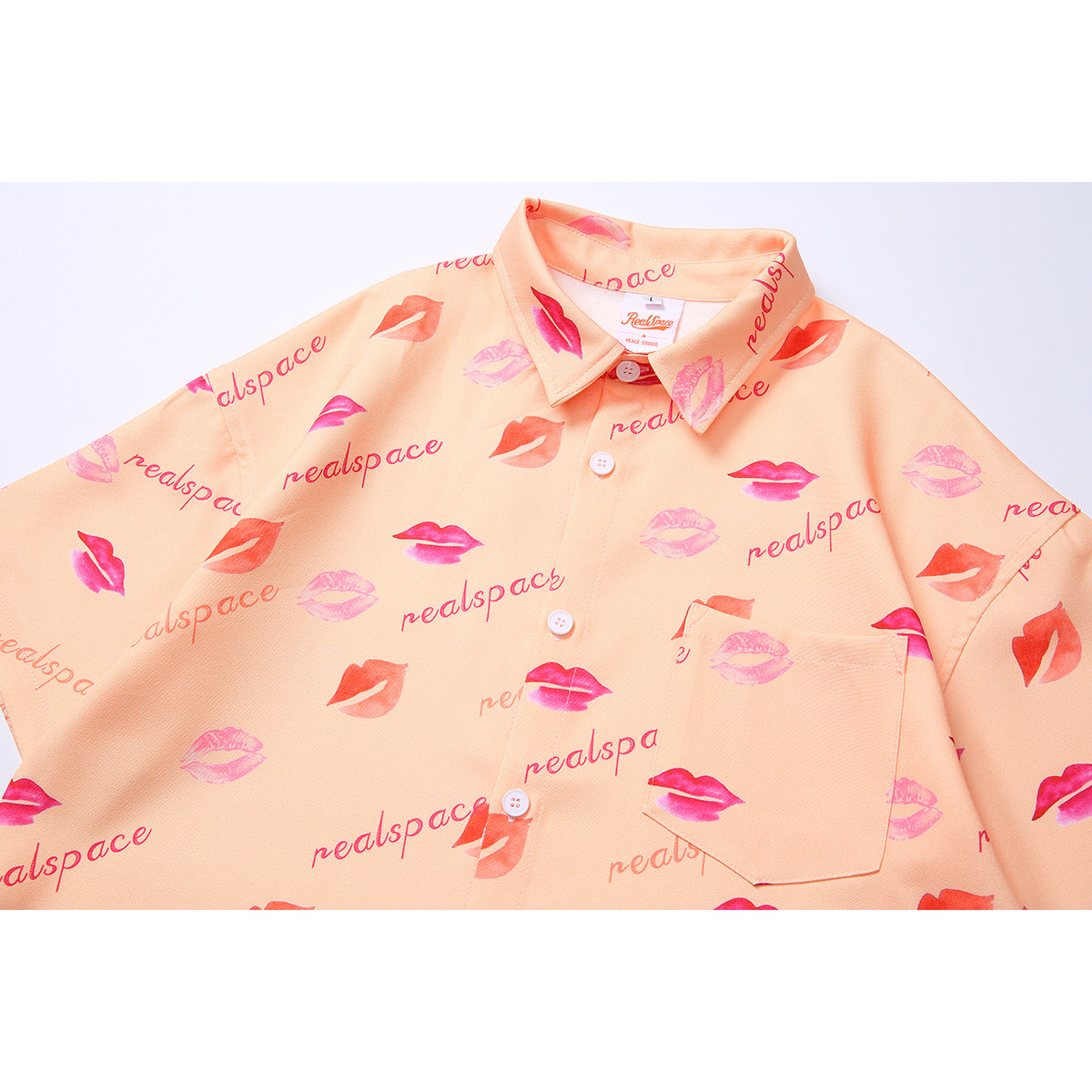 Close-up of the peach shirt's collar, buttons, chest pocket, and pink lip and text print.