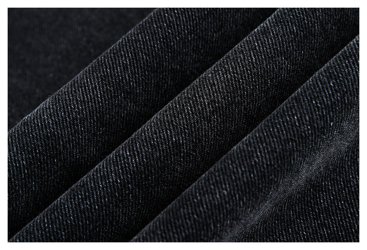 Macro close-up of black denim folds showing the textured diagonal weave.